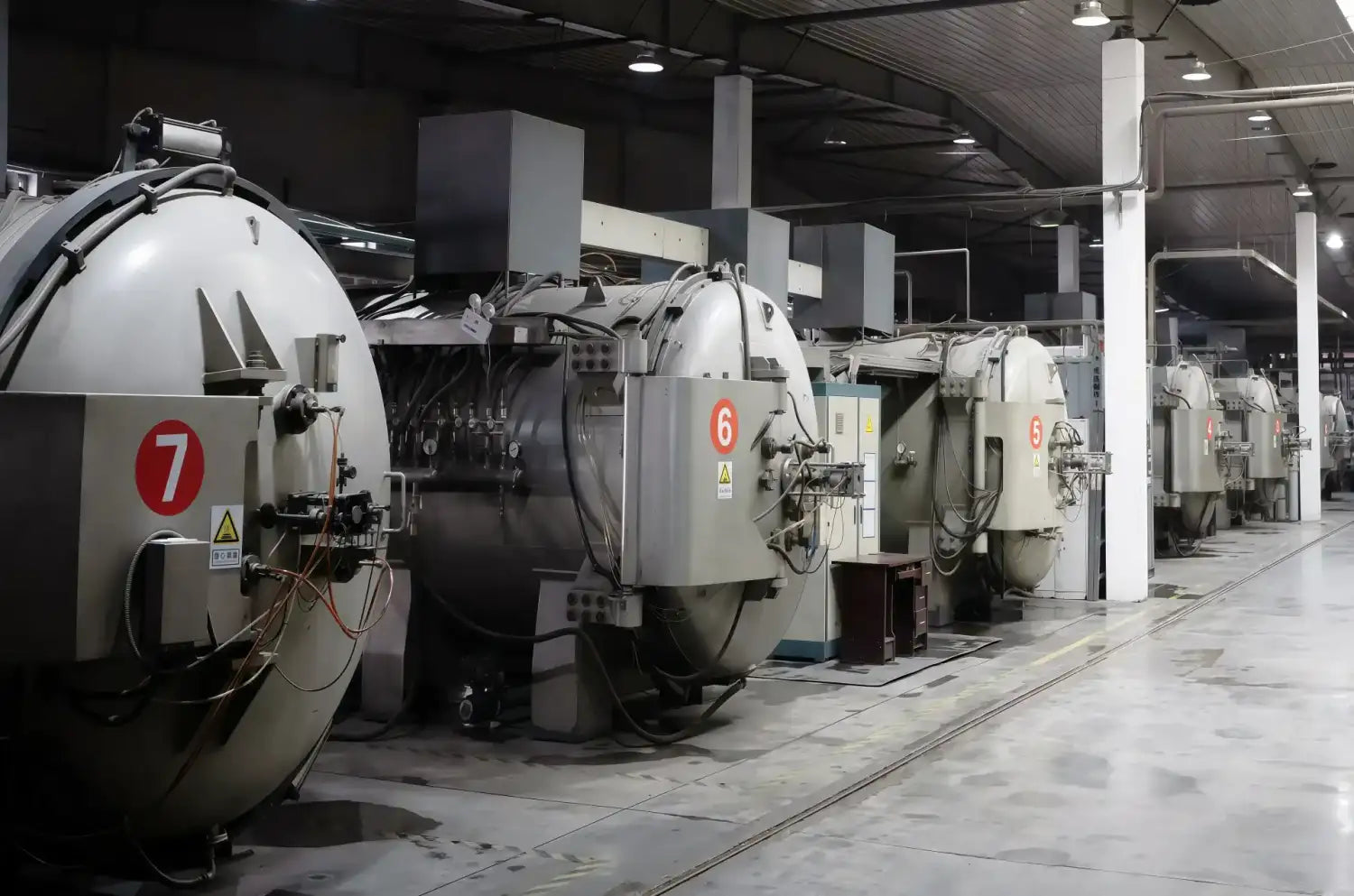 Industrial-grade vacuum chambers, numbered and marked with red circular labels on their metallic gray exteriors.